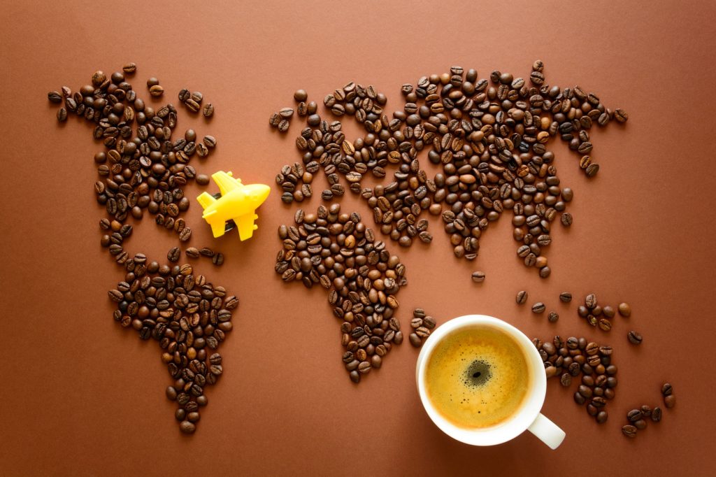 Map of the world made of roasted arabica coffee beans on brown paper background. Travel